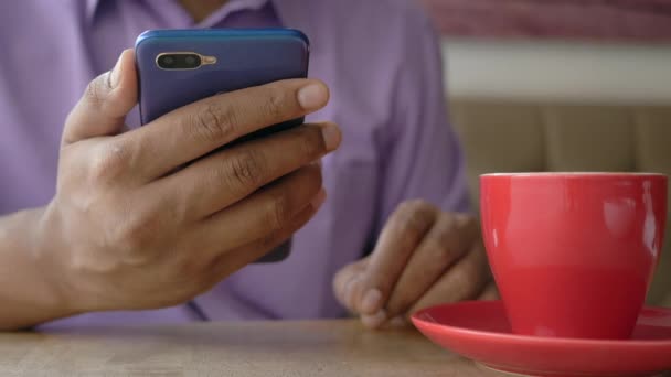 Primer plano de la mano del hombre joven usando el teléfono inteligente y beber café en la cafetería — Vídeos de Stock