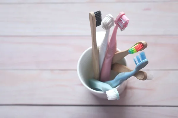Colorful toothbrushes in white mug against a wall — Stock Photo, Image
