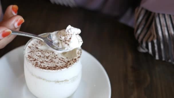 Mano de las mujeres con cuchara comer helado en la mesa de café — Vídeo de stock