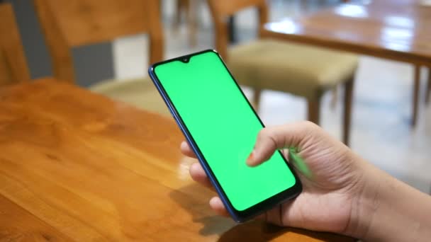 Primer plano de la mano de las mujeres jóvenes utilizando el teléfono inteligente con pantalla verde en la cafetería — Vídeos de Stock