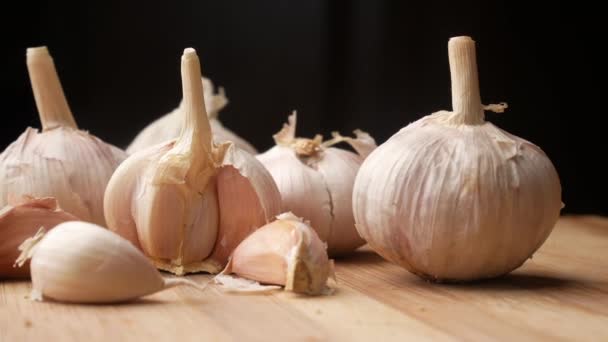 Close up pf garlic on a chopping board against black background — Stock Video