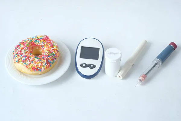 Diabetische meetinstrumenten, insuline en donuts op witte achtergrond — Stockfoto