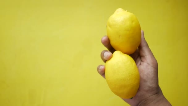 Segurando limão maduro contra fundo amarelo com espaço de cópia . — Vídeo de Stock