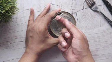 Erkek eli ahşap masada ton balığı konteynırı açıyor. ,