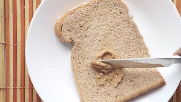Górny widok masła orzechowego i chleb na talerzu na czarnym tle — Wideo stockowe