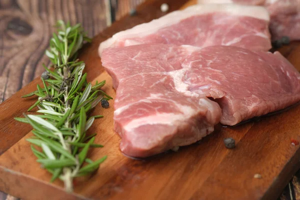 El primer plano de la carne cruda en la tabla de cortar en una tabla de cortar —  Fotos de Stock