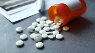  Siyah arka plana beyaz renkli tıbbi haplar dökülüyor. 