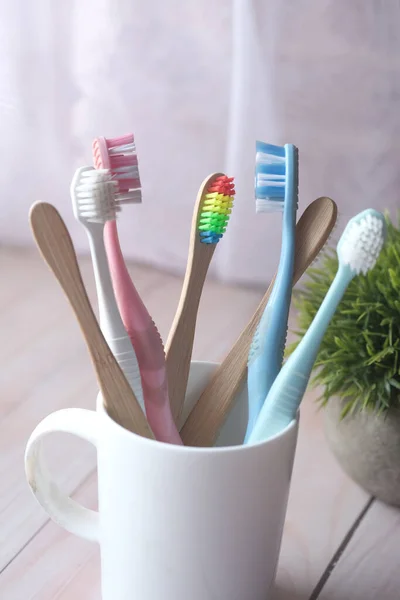 Colorful toothbrushes in white mug against a wall — Stock Photo, Image