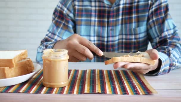 Hombre joven comiendo mantequilla de maní y perla mientras se encuentra — Vídeos de Stock