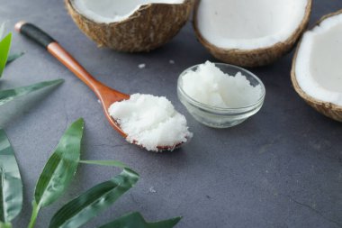 Hindistan cevizi yağlı kaşık ve siyah arka planda fındık 