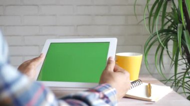 Dijital tableti yeşil ekran ile dava eden genç adamın arka görüntüsü 