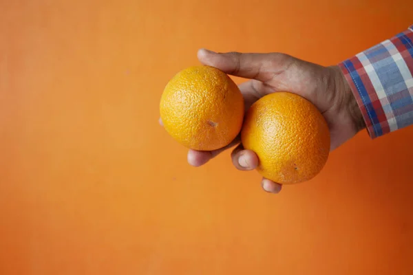 Muž ruka drží plátek pomerančového ovoce i na oranžovém pozadí — Stock fotografie