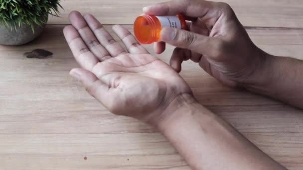 Вид сзади рук людей с лекарствами, пролитыми из контейнера с таблетками — стоковое видео
