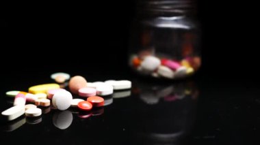 Siyah arka planda birçok renkli hap ve kapsülleri kapat 