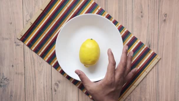 Púa de mano Amarillo limón sobre fondo de madera — Vídeos de Stock