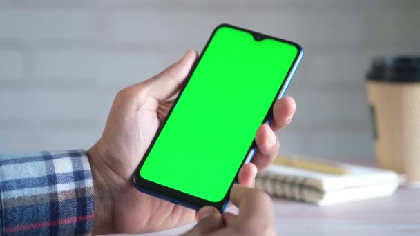 Задний вид человека рука держать смартфон с зеленым экраном белый сидит — стоковое видео