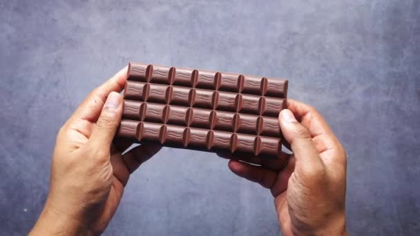 Hand houden van pure chocolade tegen zwarte achtergrond — Stockvideo
