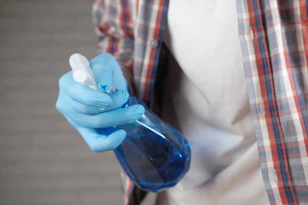 Ruka v modrých gumových rukavicích drží sprej láhev čisticí stůl — Stock fotografie