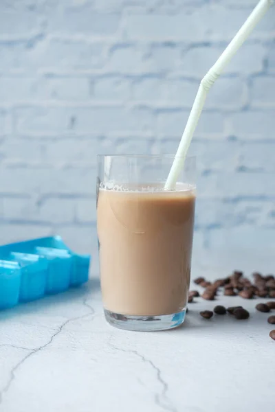 Кофе со льдом в высоком стакане с кофейными зёрнами на столе — стоковое фото