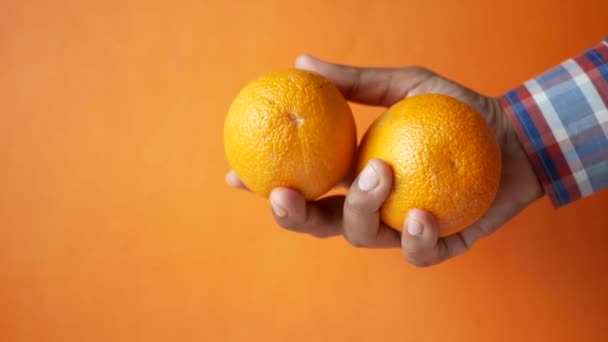 Man hand houden slice van oranje fruit i tegen blauwe achtergrond — Stockvideo