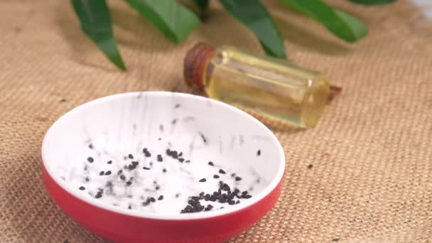 Black Cumin drops in a container with oil in a jar on table. — Stock Video