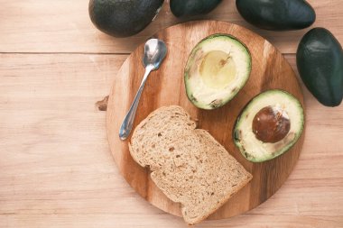 Masadaki kahverengi ekmeğin üzerindeki avokado. 