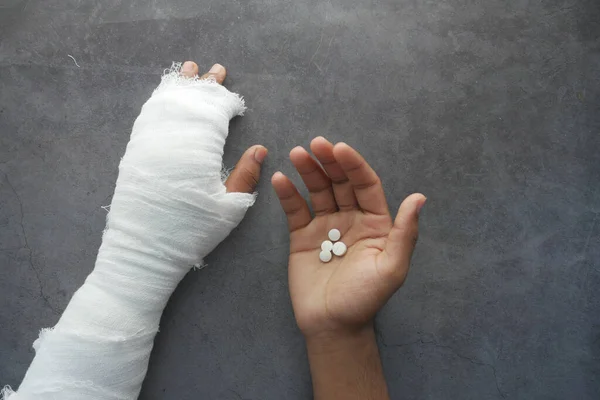 Τραυματισμένο οδυνηρό χέρι με επίδεσμο και ιατρικά χάπια στο χέρι — Φωτογραφία Αρχείου