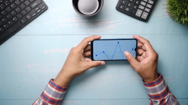 Man hand analyzing stock chart on smart phone — стоковое видео