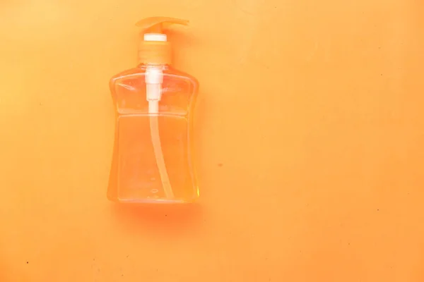 Liquide de lavage à la main dans un récipient sur fond orange — Photo