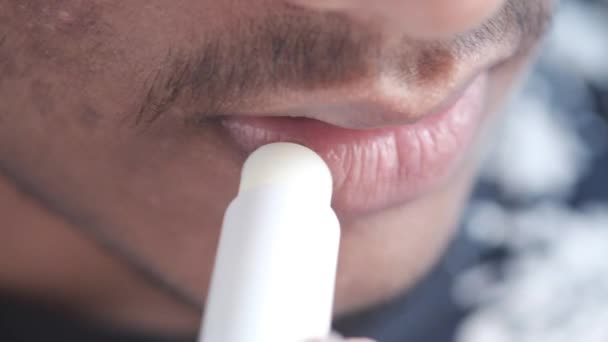 Молодой человек наносит увлажняющую помаду на губы — стоковое видео