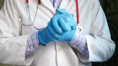 Ellerinde tıbbi eldivenlerle doktor eli destek işareti gösteriyor.,