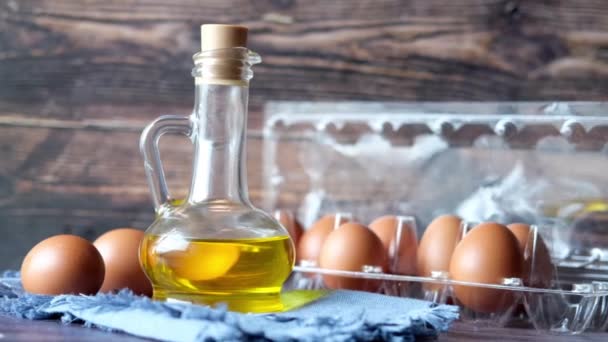 Cerrar los huevos en un recipiente de plástico y aceite de cocina en frasco sobre la mesa . — Vídeos de Stock