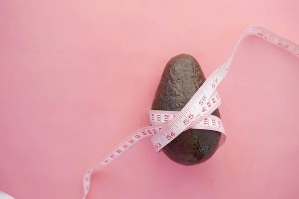 Bovenaanzicht van plak avocado en meetlint op roze — Stockfoto