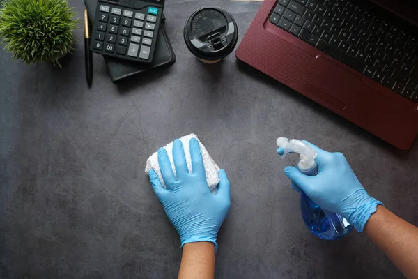 손에 스프레이 병 청소 사무실 테이블을 들고 있는 파란 고무장갑을 들고 — 스톡 사진