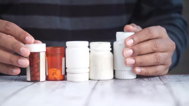 Hombre joven mano sosteniendo muchos medicamento píldora contenedor blanco sited — Vídeos de Stock