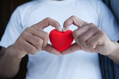  Kırmızı kalbi mavi arka planda tutan adam. 