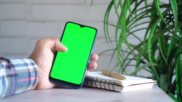 Primer plano de la mano del hombre joven utilizando el teléfono inteligente con pantalla verde — Vídeos de Stock