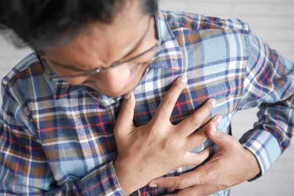 Jovem sofrendo dor no coração e segurando o peito com a mão — Fotografia de Stock