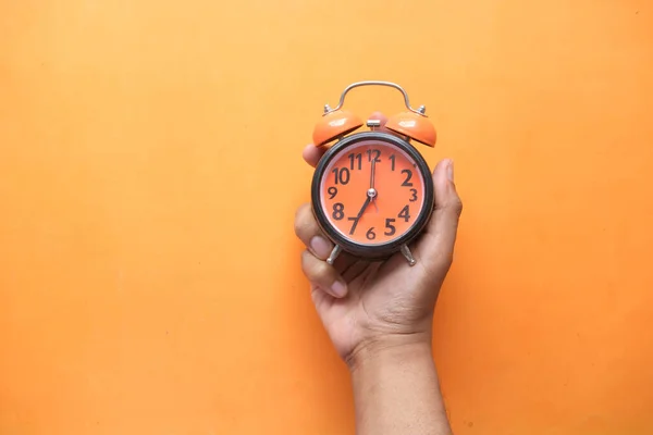 Reloj despertador de mano de persona sobre fondo naranja , —  Fotos de Stock