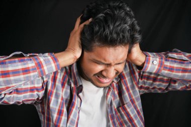 Kulak ağrısı çeken genç bir adam. Acı veren kulağına dokunuyor. 