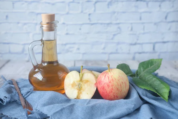 Cuka apel dalam botol kaca dengan apel hijau segar di atas meja — Stok Foto