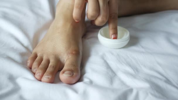 Mulher aplicando vaselina nos pés na cama — Vídeo de Stock