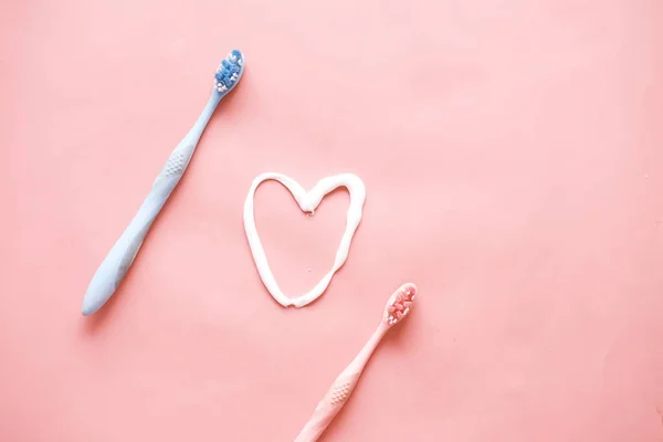 Cepillo de dientes y pasta sobre fondo rosa — Foto de Stock