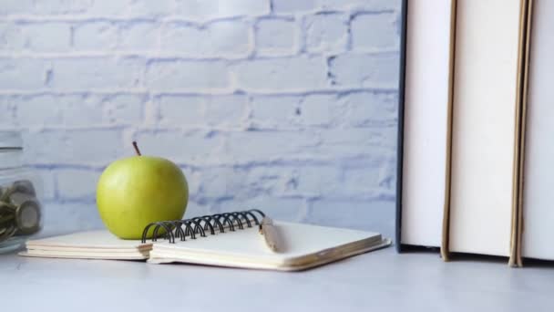 Zwart naar school concept met appel op notitieblok op tafel. — Stockvideo