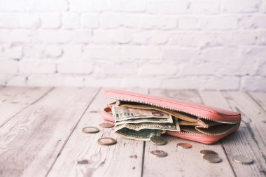 Masanın üzerinde bir dolar nakit ve deri cüzdan var.