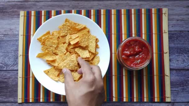 Person hand eating chips with salsa on table , — Stock Video