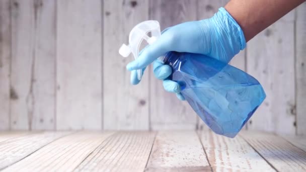 Hand i blå gummihandskar med sprayflaska rengöringsbord — Stockvideo