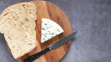 Mavi peynirin üst görüntüsü ve masada bir dilim kahverengi ekmek. 