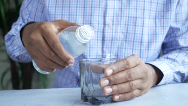 Joven vertiendo agua en un vaso sobre la mesa — Vídeo de stock