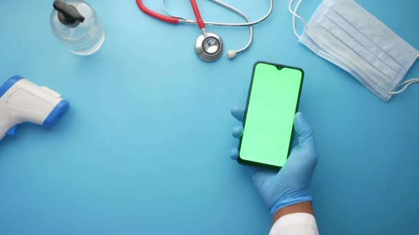 Felső nézet kéz latex kesztyű tartja okos telefon a klinika asztalon — Stock videók